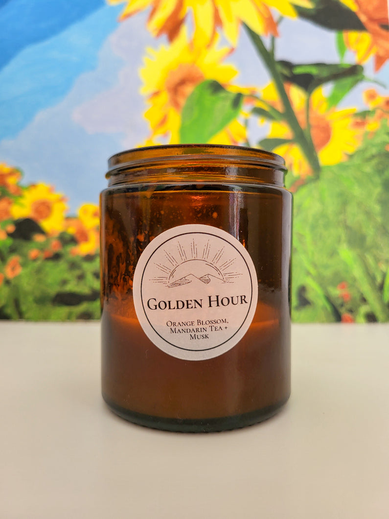 Lit candle with sunflowers painted behind